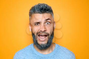 Portrait of emotional man with dyed hair and beard on color background�
