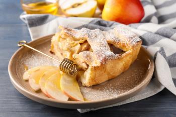 Plate with piece of delicious apple pie on wooden table, closeup�