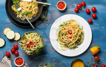 Tasty spaghetti with zucchini and sauces on color wooden table�