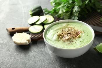 Tasty zucchini soup with pumpkin seeds in bowl on dark table�
