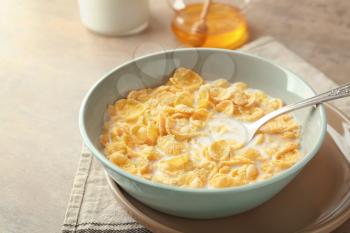 Bowl with healthy cornflakes and milk on light table, closeup�