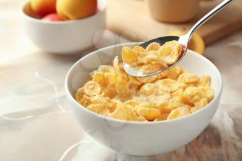 Eating of healthy cornflakes with milk from bowl on table, closeup�