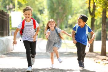 Cute little schoolchildren running outdoors�