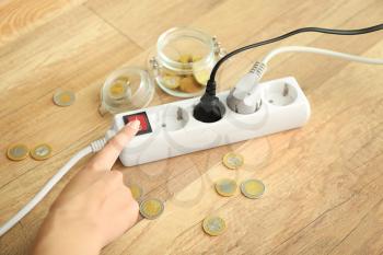Woman pressing a power button of extension cord indoors. Electricity saving concept�