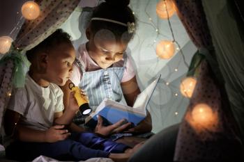 Little African-American children reading bedtime story in hovel�