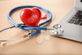 Medical stethoscope and red heart on light table. Cardiology concept�