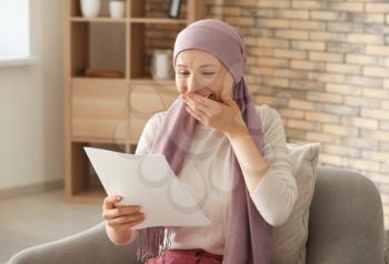 Happy woman after chemotherapy reading test results at home�