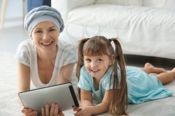 Little girl and her mother after chemotherapy using tablet PC at home�