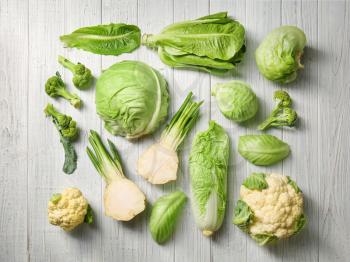 Different types of cabbage on light wooden background�