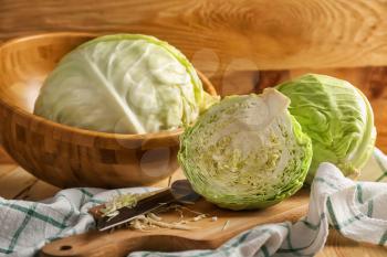 Whole and cut fresh cabbage on wooden table�