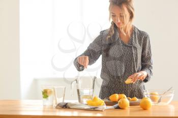 Young woman preparing fresh lemonade at home�
