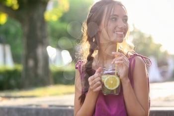 Young woman with mason jar of fresh lemonade outdoors�