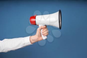 Woman holding megaphone on color background�