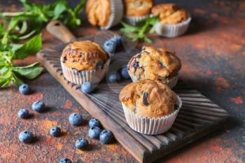 Tasty blueberry muffins on wooden board�