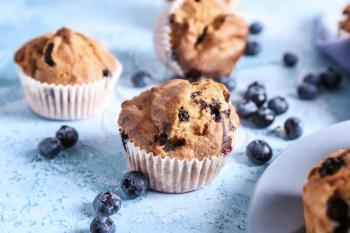Tasty blueberry muffins on color background�