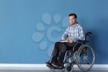Young man in wheelchair near color wall�