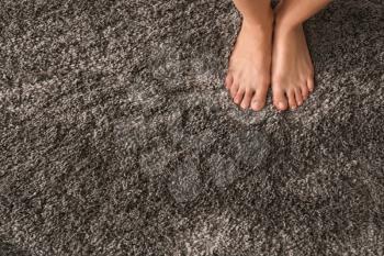 Legs of barefoot woman standing on fluffy carpet�