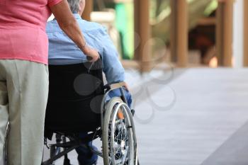 Senior man in wheelchair and his wife on ramp outdoors�