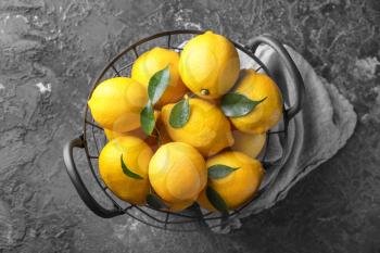 Metal basket with ripe lemons on grey table�