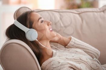 Beautiful young woman listening to music at home�
