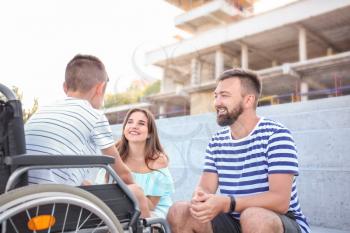 Teenage boy in wheelchair with his family outdoors�