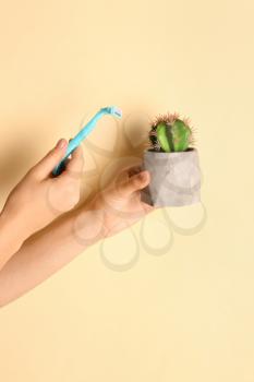Woman holding razor and cactus on color background�