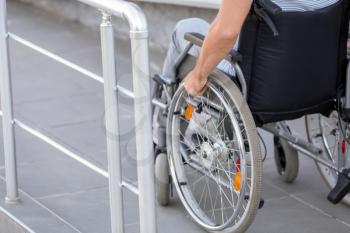 Young man in wheelchair on ramp outdoors�