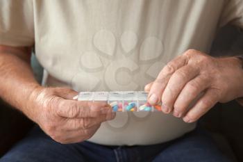 Senior man holding container with pills, closeup�