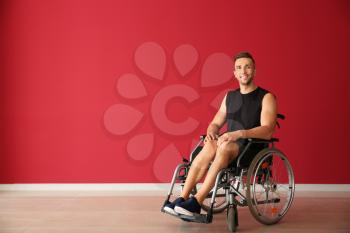 Young man sitting in wheelchair near color wall�
