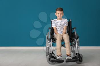 Boy in wheelchair against color wall�