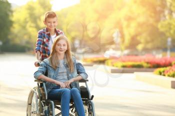 Teenage girl in wheelchair and her brother outdoors�