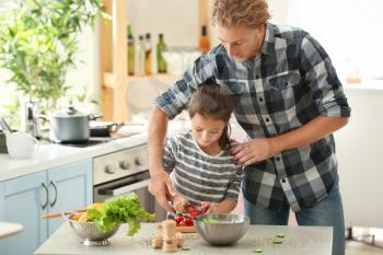 Father and daughter cooking together in kitchen�