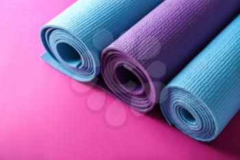 Different yoga mats on color background�