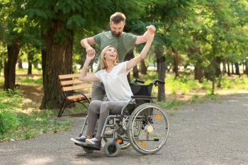 Beautiful woman in wheelchair with man dancing outdoors�