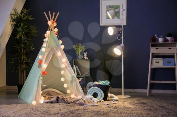 Cozy play tent for kids with glowing garland in room interior�