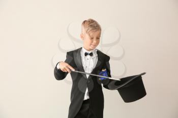 Cute little magician showing trick with hat on white background�