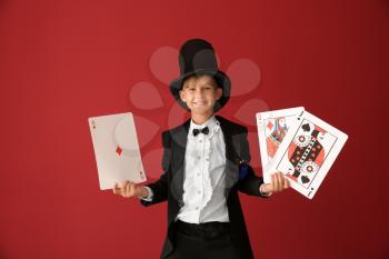 Cute little magician with cards on color background�