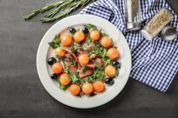 Delicious salad with melon balls and prosciutto on plate, top view�
