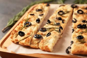 Traditional Italian Focaccia with rosemary and olives on wooden board, closeup�