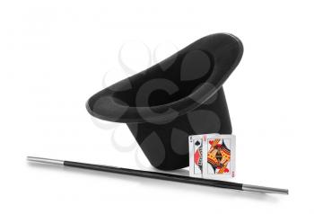 Black hat, magic wand and cards on white background�