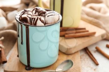 Metal cup of hot chocolate with marshmallows on wooden board�