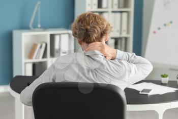Businessman suffering from neck pain in office�