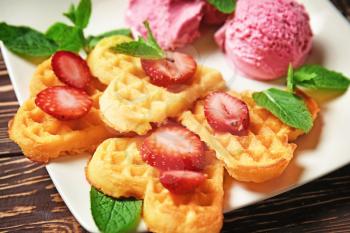 Heart shaped waffles with strawberries and ice cream on plate, closeup�