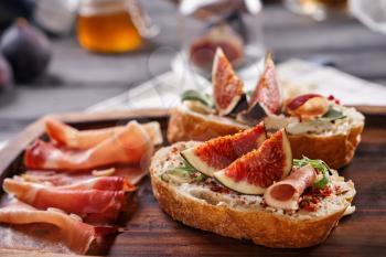 Tasty sandwiches with ripe fig and prosciutto on wooden board�