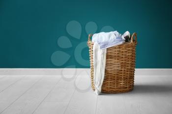 Laundry basket with dirty clothes on floor near color wall�