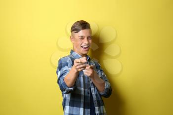 Smiling teenage boy pointing at viewer on color background�