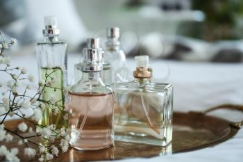 Bottles of perfume with flowers on metal tray�