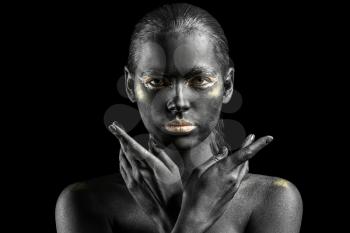 Beautiful woman with black and golden paint on her body against dark background�