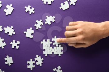 Hand of woman doing puzzle on color background 