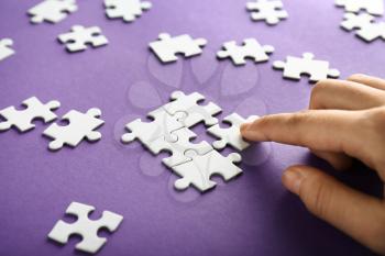 Hand of woman doing puzzle on color background, closeup�